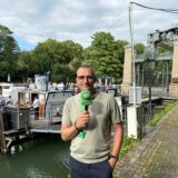 Reporter Jürgen Bröker steht am Ufer eines Kanals im Hintergrund ist ein Schiff zu sehen.