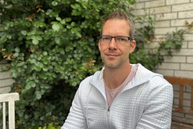 Bastian Himmeröder sitzt im Garten seines Elternhauses. Er hat ein weißes Shirt an.