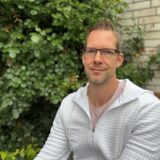 Bastian Himmeröder sitzt im Garten seines Elternhauses. Er hat ein weißes Shirt an.