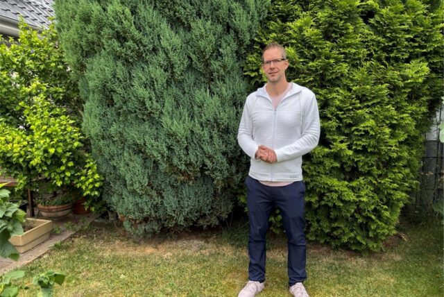 Bastian Himmeröder sitzt im Garten seines Elternhauses. Er hat ein weißes Shirt an.