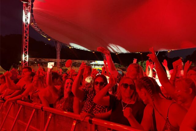 Im roten Licht feiern tausende Menschen vor der Bühne beim Sunset Beach Festival.