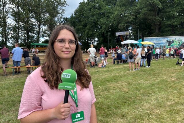 Reporterin Lara Teschers steht mit WZ-Mikrofon beim Trecker-Treck.