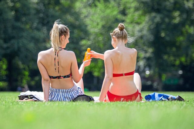 Zwei junge Frauen sonnen sich auf einer Wiese.