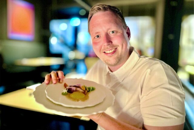 Ruhr-Nachrichten-Reporter Fabian Hollenhorst hält einen Teller aus dem Menü des Restaurants SchwarzGold in Dortmund in die Kamera.