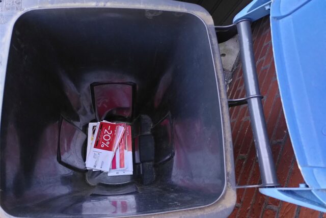 Geöffnete Papiertonne mit Briefen am Boden.