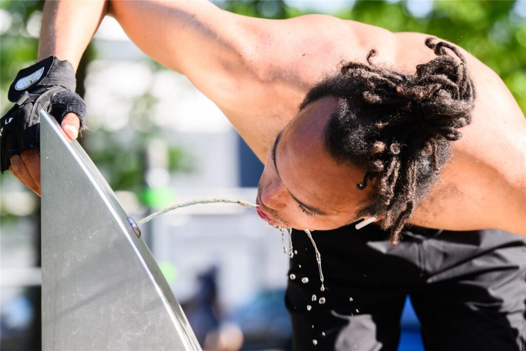 Ein Mann trinkt aus einem Wasserspender. 
