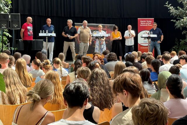 Stefan Springer (von links), Bernhard Felling, Moderator Stefan Prott, Andreas Hebestreit, Babette Nieder, Moderatorin Laura Tirier-Hontoy, Fred Toplak und Patrick Berner stehen im Glashaus Herten auf der Bühne vor einem Publikum.