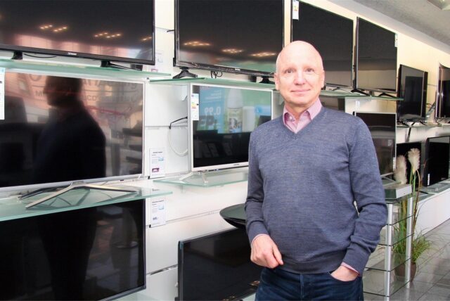 Peter Schiefelbein steht vor Regalen mit Fernsehern in seinem ehemaligen Elektrofachgeschäft in Dortmund-Marten.