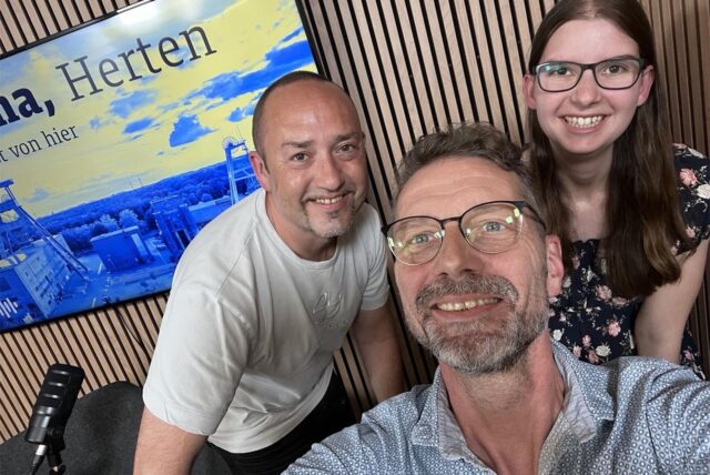 Die drei Redakteure André Przybyl, Harald Landgraf und Katharina Göke (v.l.) posieren vor einem Fernseher mit einer Grafik von Herten für die Kamera.