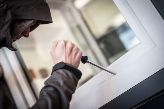 Ein Mann mit einem Schraubendreher an einem Fenster.