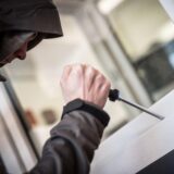 Ein Mann mit einem Schraubendreher an einem Fenster.
