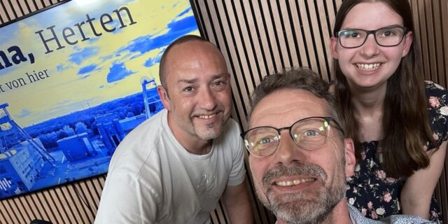 Die drei Redakteure André Przybyl, Harald Landgraf und Katharina Göke (v.l.) posieren vor einem Fernseher mit einer Grafik von Herten für die Kamera.