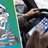 Jemand schaut beim Autofahren auf sein Handy.