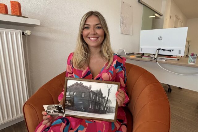 Leonie Becker sitzt mit alten Bildern des Hauses Molkereistraße 1 in einem Sessel in ihren Geschäftsräumen.