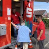 Eine Frau steigt in den Sparkassenbus ein, zwei Männer helfen ihr.
