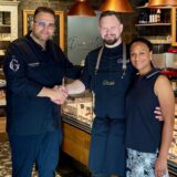 Daniel Georgiev (l.) schüttelt im Delikatessenladen die Hand von Milan Makovy, an dessen Seite Ehefrau Jennifer Adu-Makovy steht.