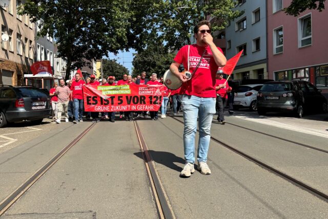Bereits im Sommer 2024 hatte die Belegschaft von Thyssenkrupp in Dortmund gegen den drohenden Stellenabbau protestiert. Moritz Engels, Betriebsratschef, steht hier vor der Demo und spricht durch ein Megafon.