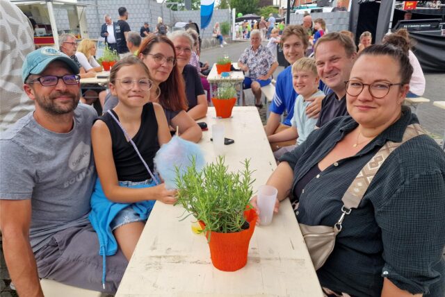 Zwei Familien sitzen beim Tag der offenen Tür der Hertener Stadtwerke auf deren Betriebshof an einem Tisch und schauen freundlich in die Kamera.