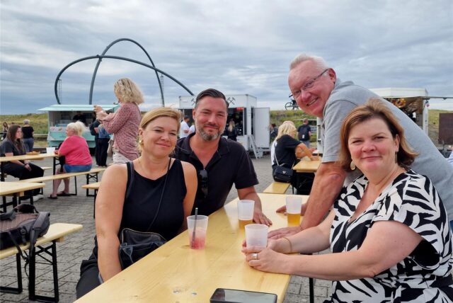 Zwei Paare sitzen beim Street-Food-Picknick auf der Halde Hoheward. Im Hintergrund ist das Horizont-Observatorium zu sehen.