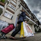 Eine Frau geht mit zwei Tüten und einem Einkaufsroller am Hannibal-Gebäude vorbei.