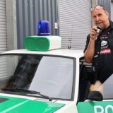 Jörg Lange steht an einem Polizeiwagen.