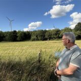 Andreas Lamberty vor einem Feld in Ellinghausen. Im Hintergrund die Windräder der „EllWira“-Anlage.