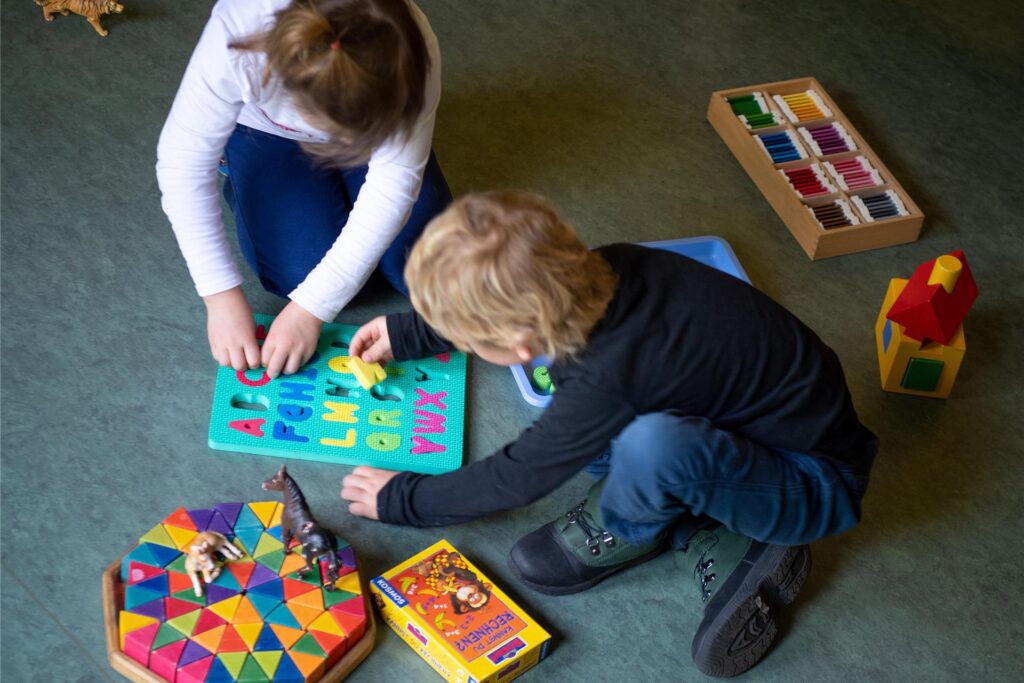 Ein Junge und ein Mädchen spielen in einem Kindergarten auf dem Boden. Ein Junge und ein Mädchen spielen in einem Kindergarten auf dem Boden.