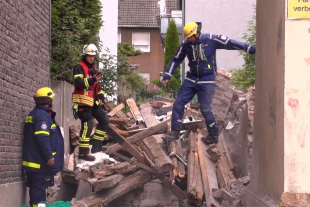 Einsatzkräfte des THW auf einem Berg Bauschutt an der Provinzialstraße in Bövinghausen.