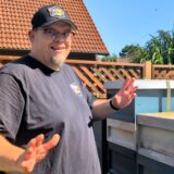 Imker Patrick Kramer steht in seinem Garten vor seinen Bienenvölkern.