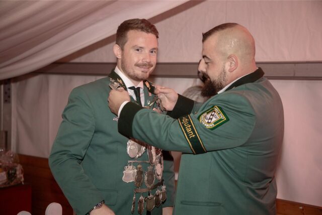 Kaiseradjutant Daniel Baak (r.) hilft Kaiser Dennis (I.) Pieper beim Wechseln der Kaiserkette im heißen Festzelt der Erntegemeinschaft Waltrop Rieselfeld.