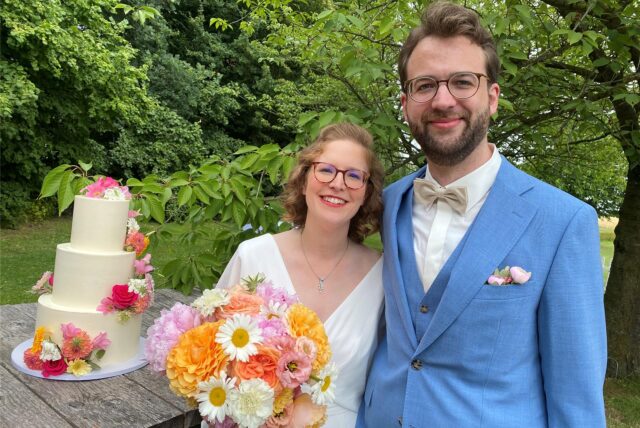 Das Hochzeitspaar Caroline Reddemann und Marius Bilke steht vor der Hochzeitstorte.
