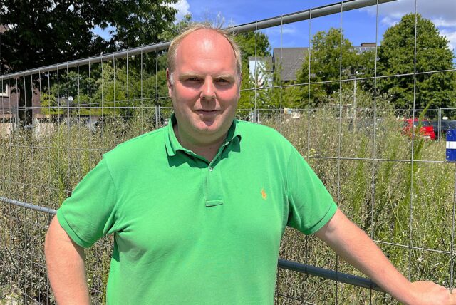 Carsten Abenhardt steht vor einem Bauzaun.