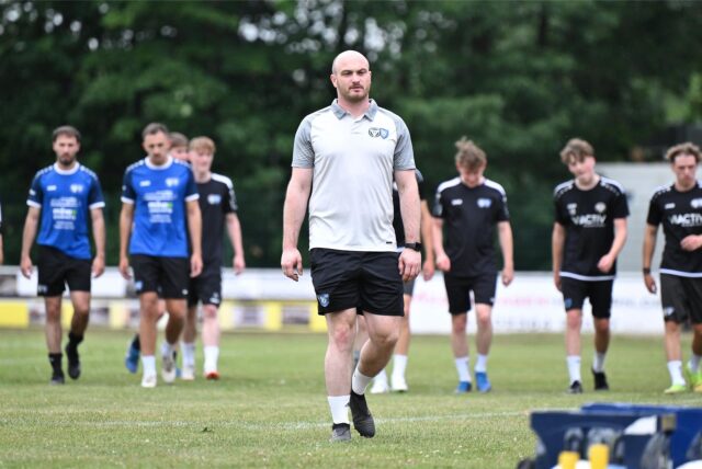 TuS Halterns Co-Trainer Marcel Tost Beim Trainingsauftakt auf dem Feld. Im Hintergrund sind einige TuS-Spieler zu sehen.