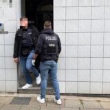 Zwei Polizisten stehen in einem Hauseingang bei einer Razzia in NRW.