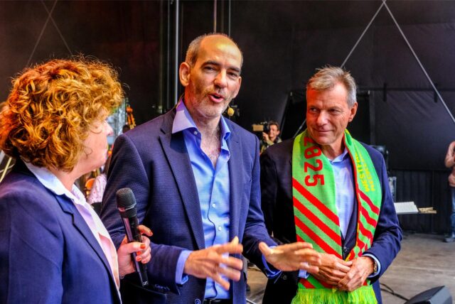 Moderatorin Steffi Neu, NPW-GMD Rasmus Baumann und Recklinghausens Bürgermeister Christoph Tesche stehen nach dem gelungenen Weltrekord mit dem größten Streichorchester auf der Bühne.