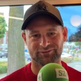 Ein Mann lächelt in die Kamera, er nimmt an unserer Umfrage teil.