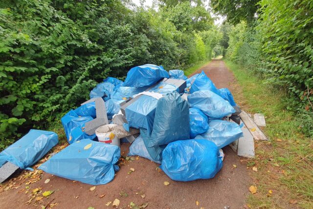 Blaue Säcke mit Dämmmaterialien liegen auf einem Fußweg.