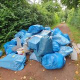 Blaue Säcke mit Dämmmaterialien liegen auf einem Fußweg.