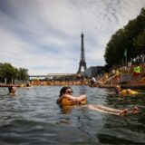 Menschen genießen das Wasser an der sicheren Badestelle Grenelle an der Seine in Paris. Im Hintergrund ist der Eifelturm zu sehen.