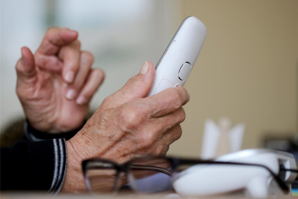Zwei ältere Hände halten ein Telefon. Zwei ältere Hände halten ein Telefon.