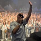 DJ Moguai mit einem Mikro in der Hand vor einer feiernden Menge.