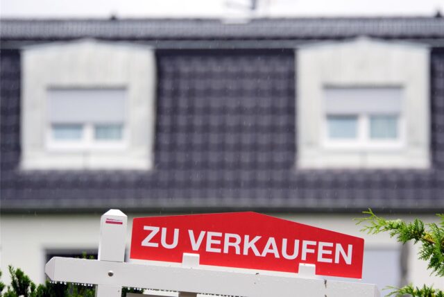 Ein Schild mit der Aufschrift „Zu verkaufen“ vor einem Haus