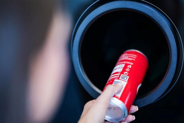 Ein Kunde steckt eine Dose in den Pfandautomaten.
