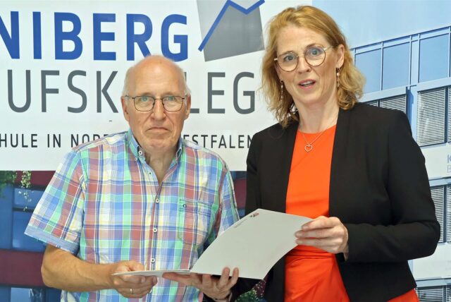 Berthold Lange und Schulleiterin Michaela Korte halten die Urkunde zum Jubiläum in den Händen und posieren für die Kamera.