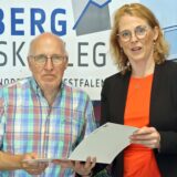 Berthold Lange und Schulleiterin Michaela Korte halten die Urkunde zum Jubiläum in den Händen und posieren für die Kamera.