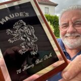 Rick Healy hält eine Tafel seines früheren Regiments in die Kamera. Neun Jahre lang war der ehemalige britische Soldat, der heute in Fröndenberg lebt, in Dortmund stationiert.