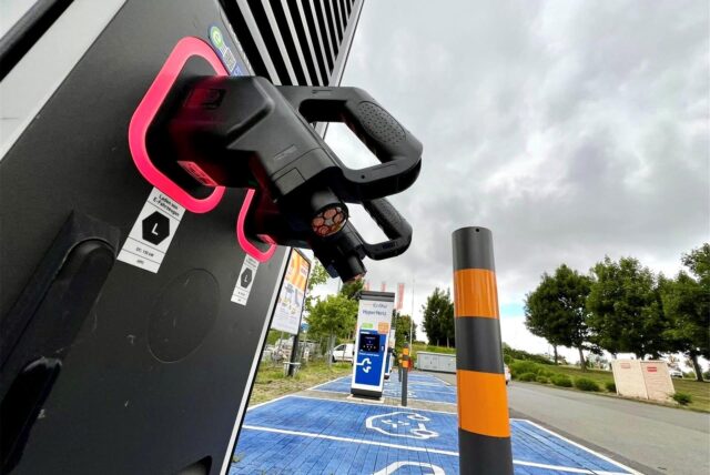 Man sieht zwei Ladepistolen einer Elektroladestation. Die Kabel der Pistolen sind bis oben abgetrennt. Die Kupferenden sind zu erkennen.