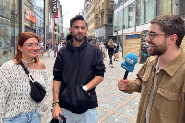 Ein Reporter spricht mit zwei Passanten.