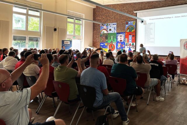 Kreisfußballausschuss-Chef Erhard Korinth präsentiert in der Mensa der Wolfgang-Borchert-Gesamtschule die mit Spannung erwartete Staffeleinteilung