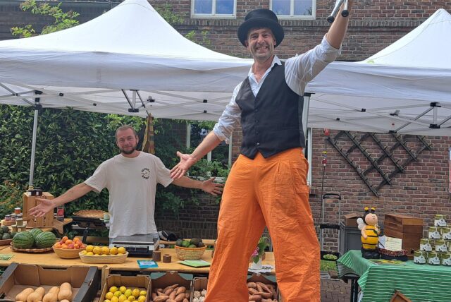 Ein Mann auf Stelzen und ein Marktstand.